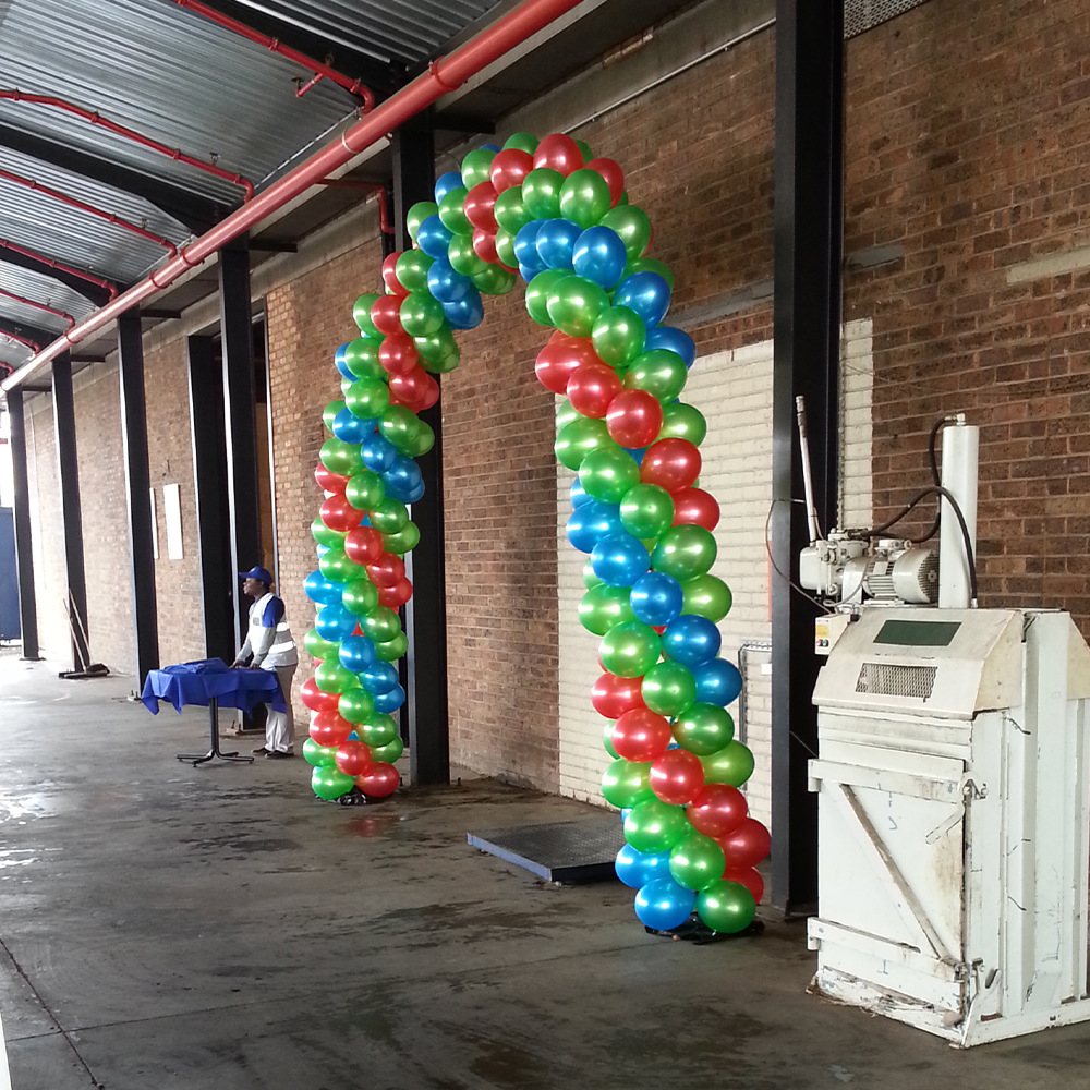 Bright red, green, and blue balloon arch in a warehouse setting