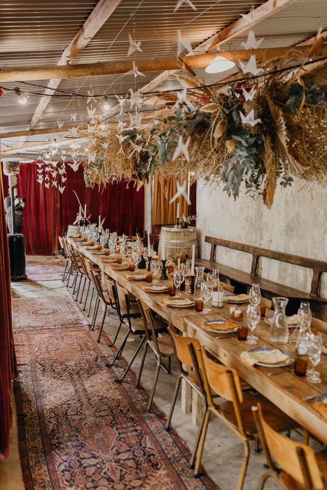 Long banquet table set with glassware, utensils, and decorative elements.