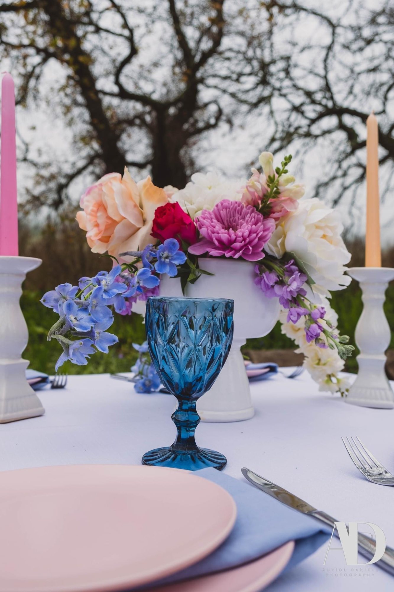Table setting with flowers, blue glassware, and pastel plates