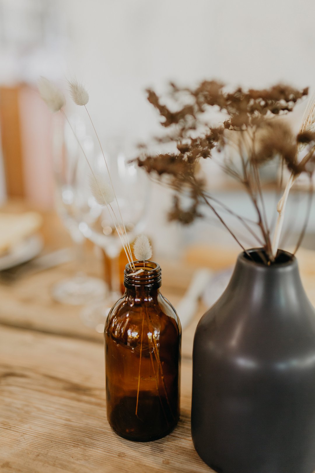 Amber glass bottle and dark vase with dried flowers
