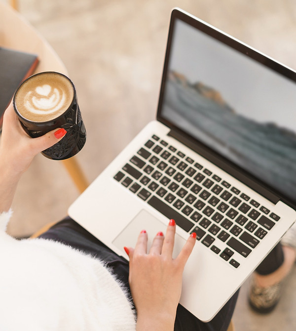 Person with coffee using a laptop on a table