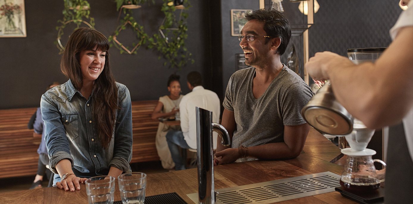Customers smiling at each other in a coffee bar