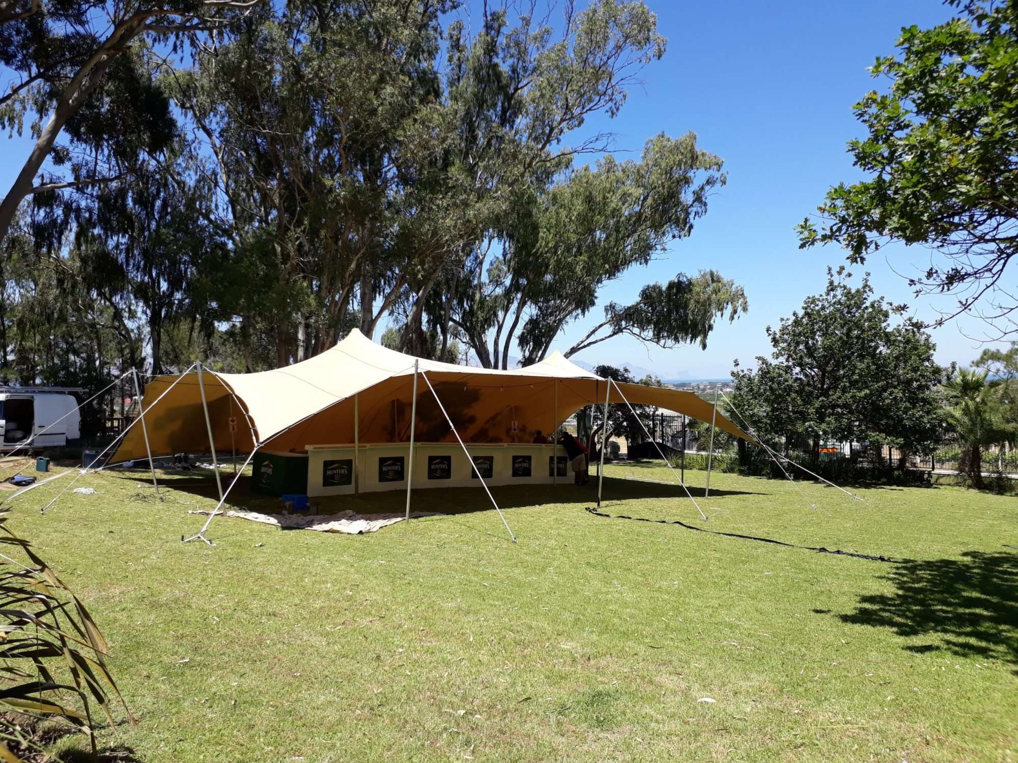 A stretch tent being set up on a grassy area.