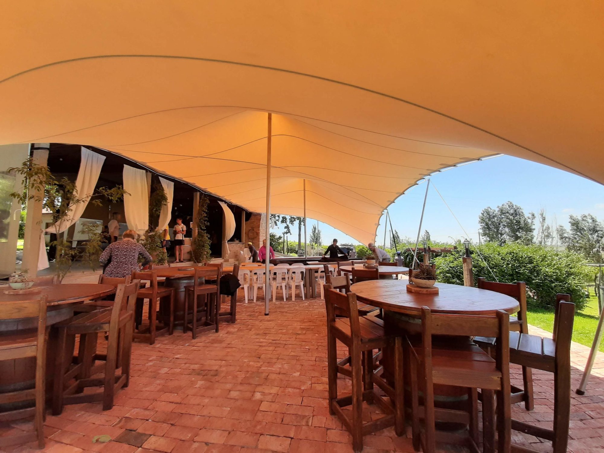 Outdoor stretch tent setup with wooden tables and chairs