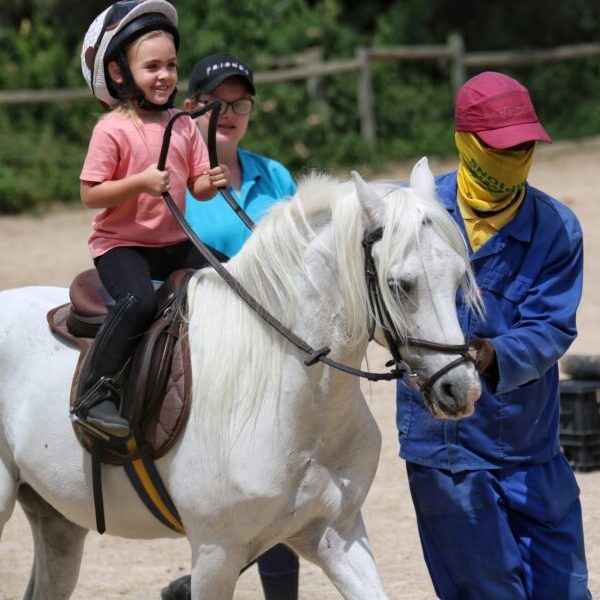 Child riding a pony with assistance at Sun Valley Stables