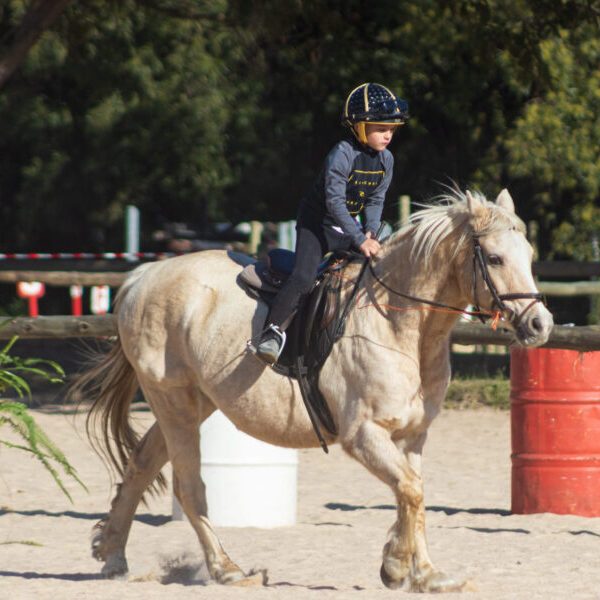 Child riding a pony in an outdoor area