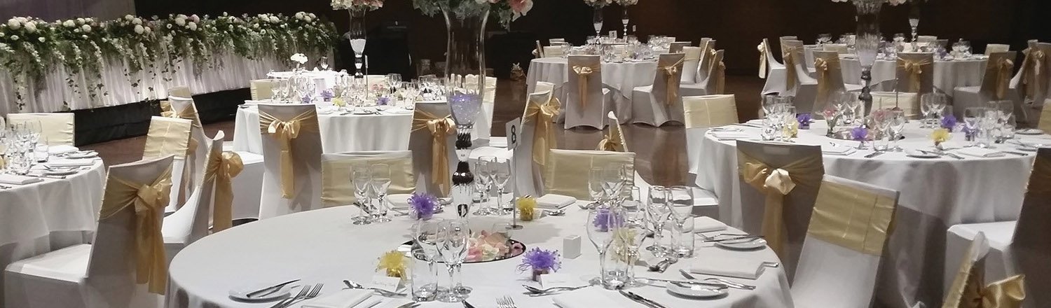 Wedding reception setup with round tables and decorated chairs