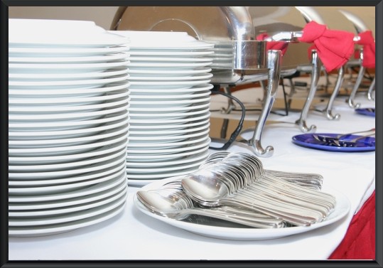 Stacks of plates and utensils ready for a catering event