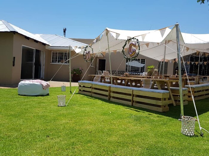 Outdoor event with a canopy tent and wooden seating