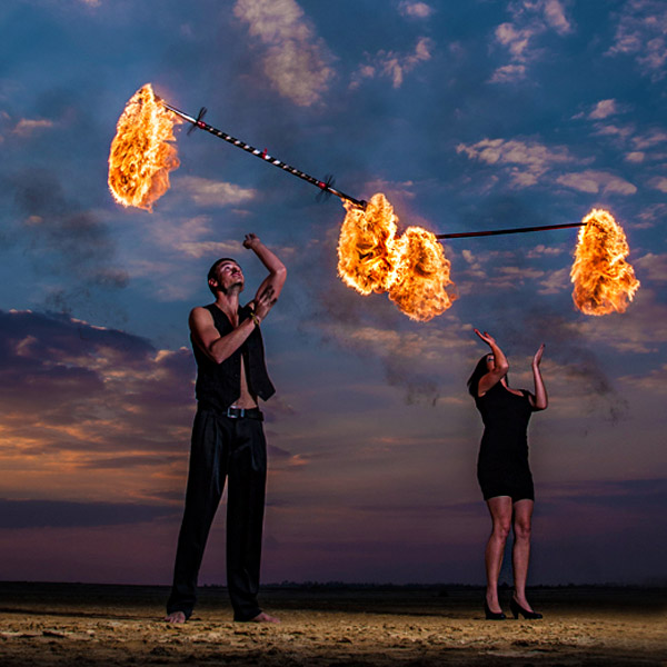 Two performers executing a fire dance at dusk