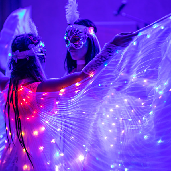 Two dancers showcasing LED wings at an event