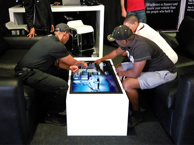 Two guests interacting with a touch screen table at an event.