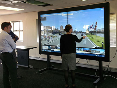 Two people interacting with a large touch screen display.