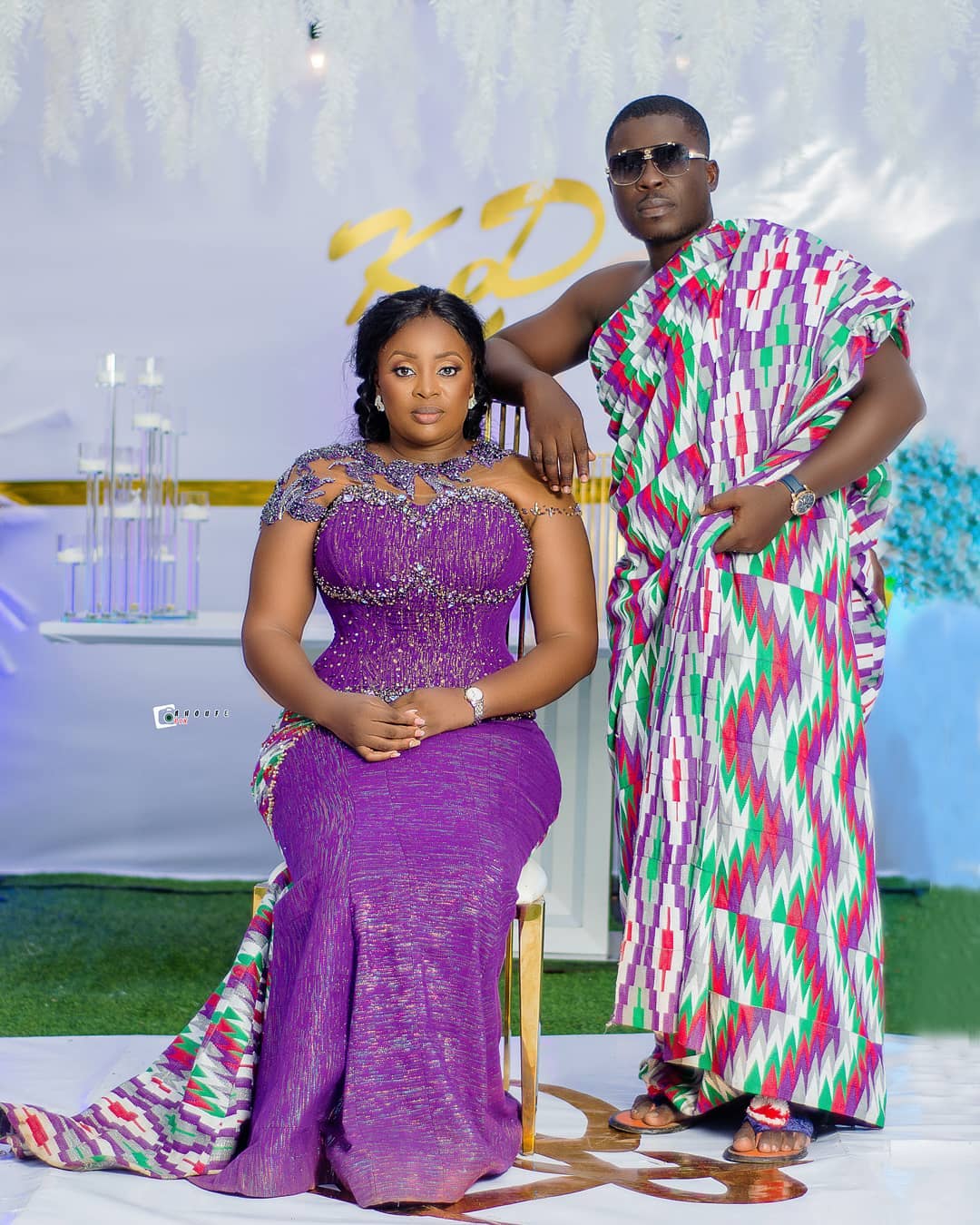 Couple in traditional attire posing for a photograph in festive decor.
