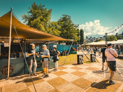 Outdoor event with guests near a stretch tent booth.