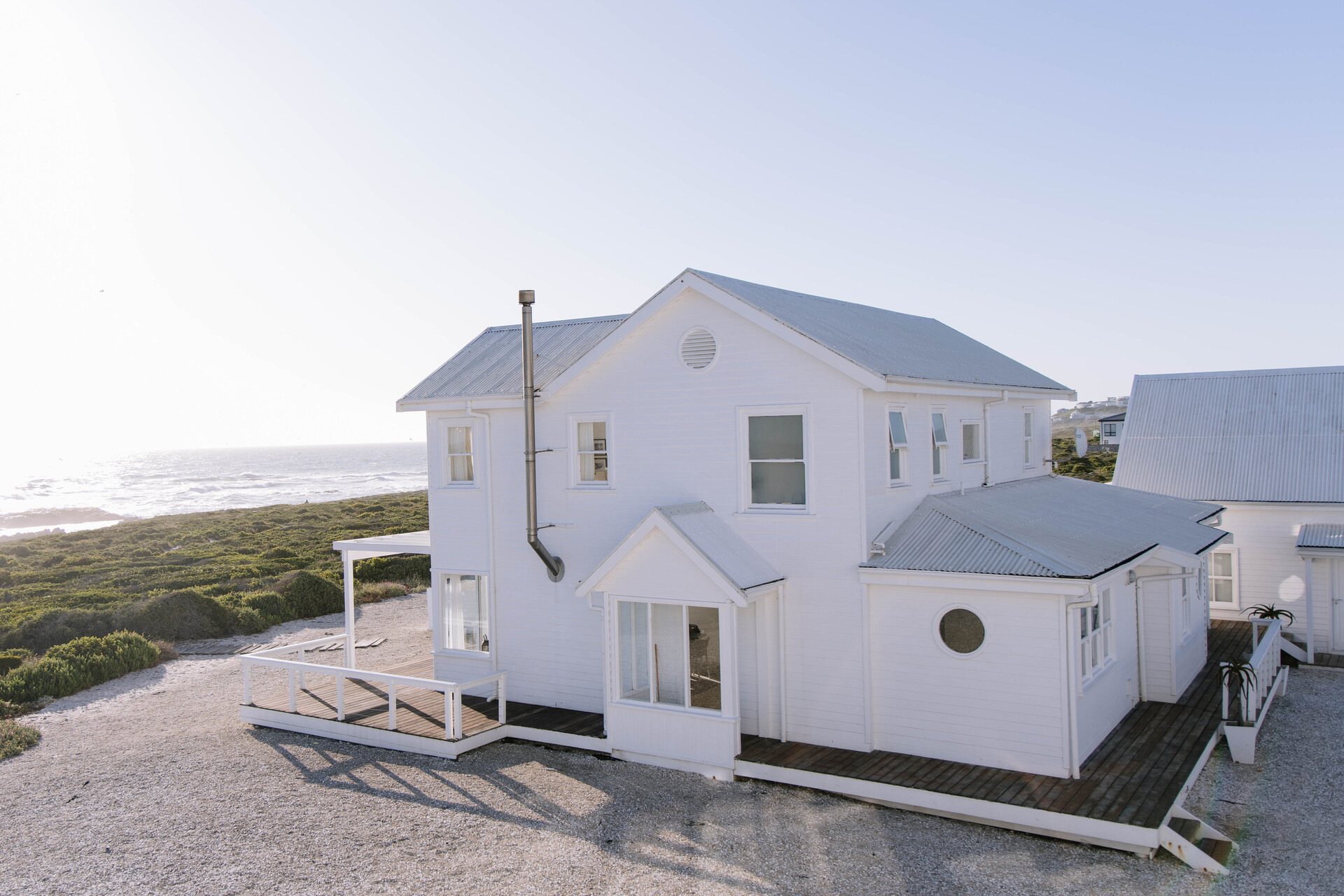 Exterior view of a white beach house near the ocean