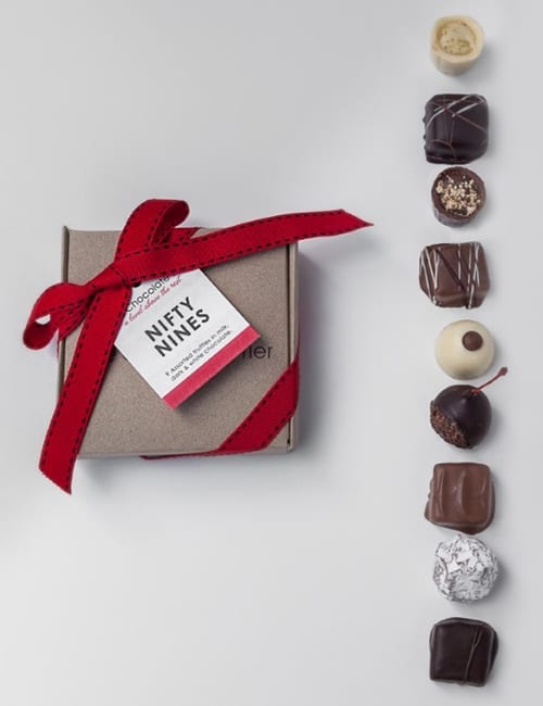 A box of nine assorted chocolates with a red ribbon.