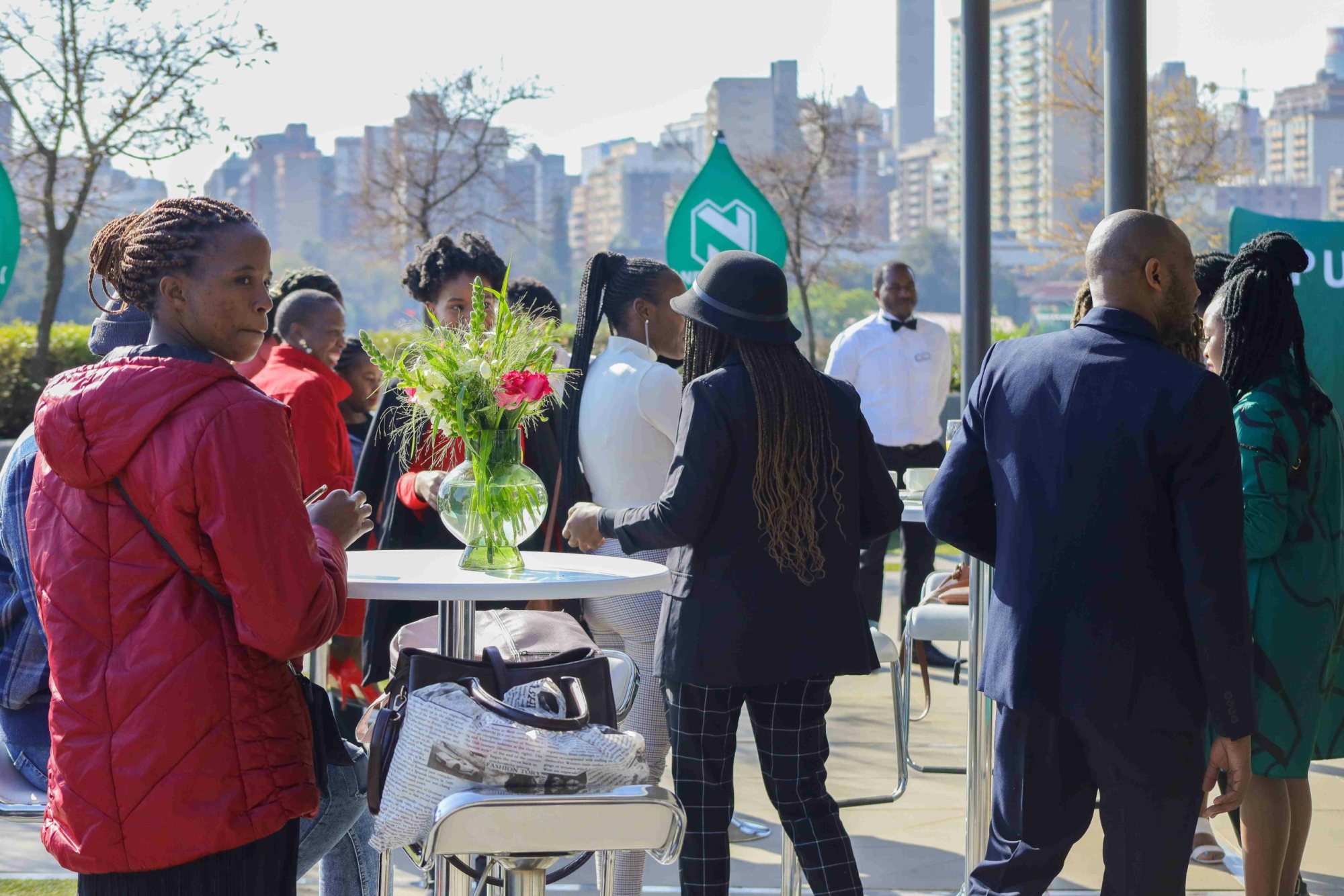 Attendees mingling at a rooftop event with cityscape background.