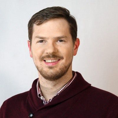 A smiling bartender in a maroon sweater