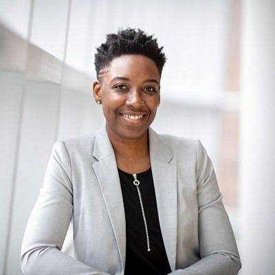 Woman in a grey blazer smiling at the camera