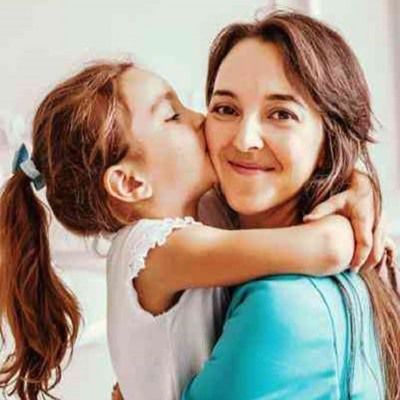 Young girl hugging and kissing her mother on the cheek.
