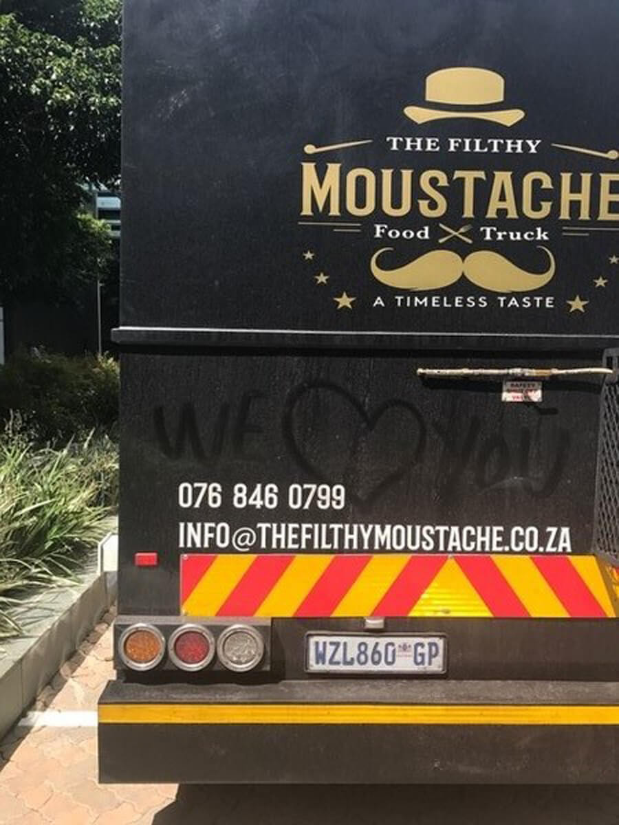 Back of The Filthy Moustache food truck with contact info and graffiti.