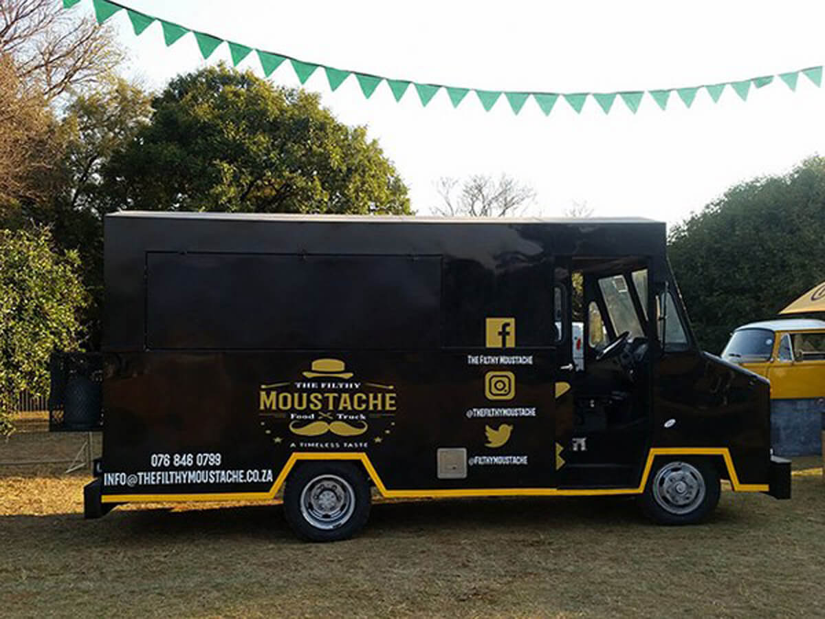 Black food truck with yellow details parked outdoors