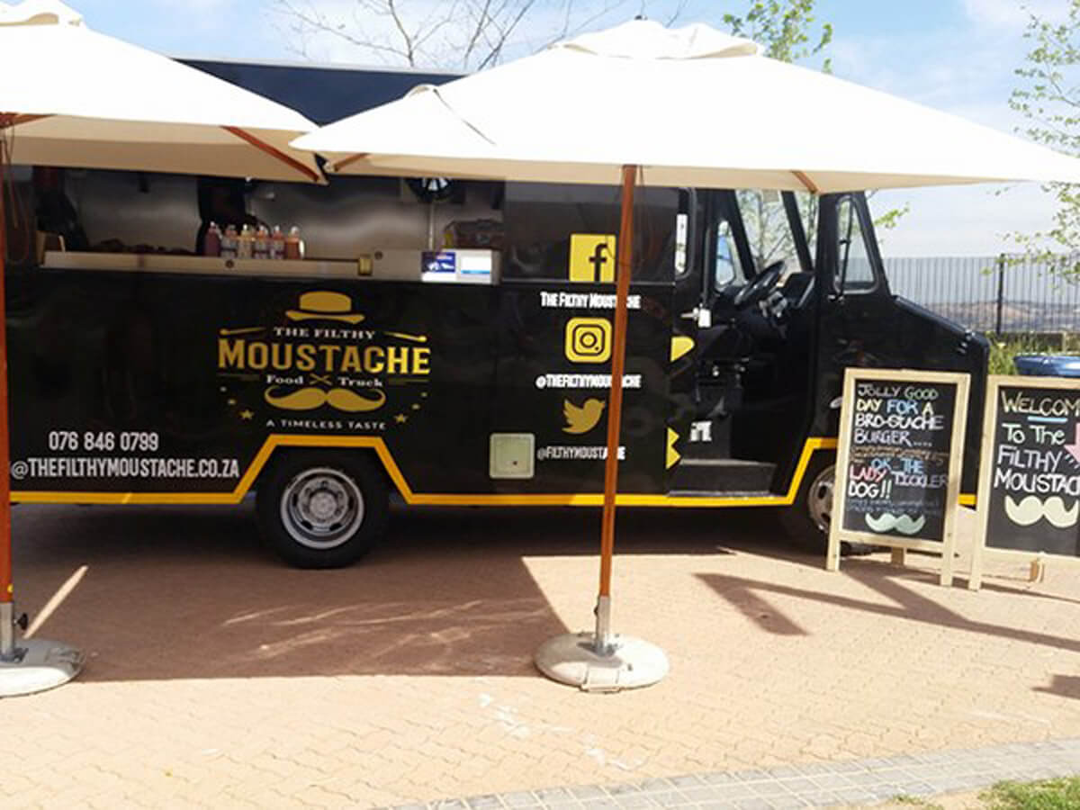 The Filthy Moustache food truck with umbrellas and a menu sign