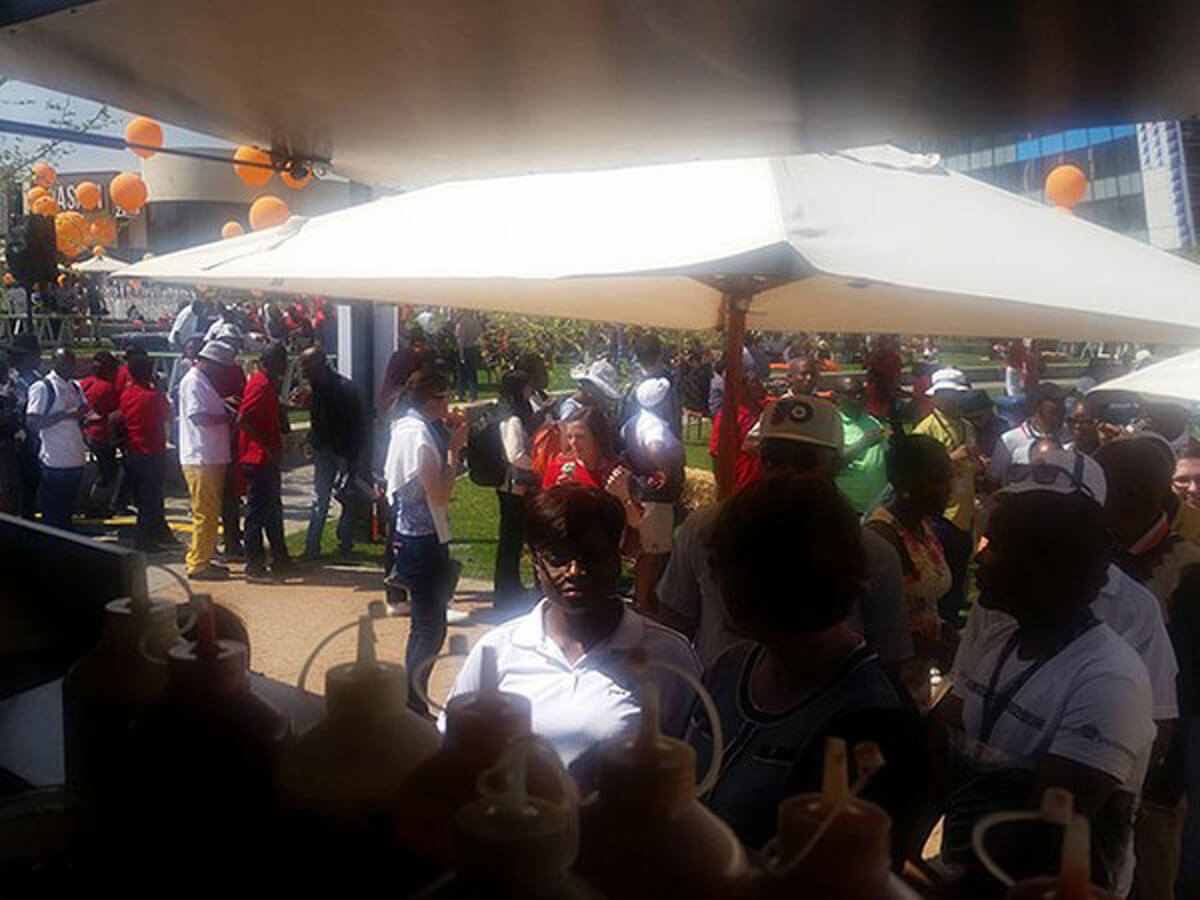 Crowd at a food truck event under large umbrellas