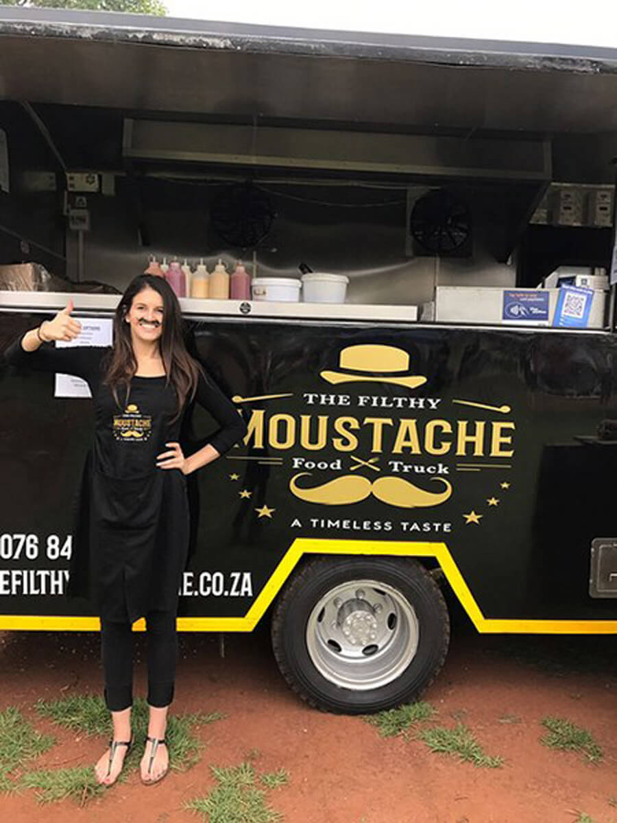 Staff member beside The Filthy Moustache coffee truck.