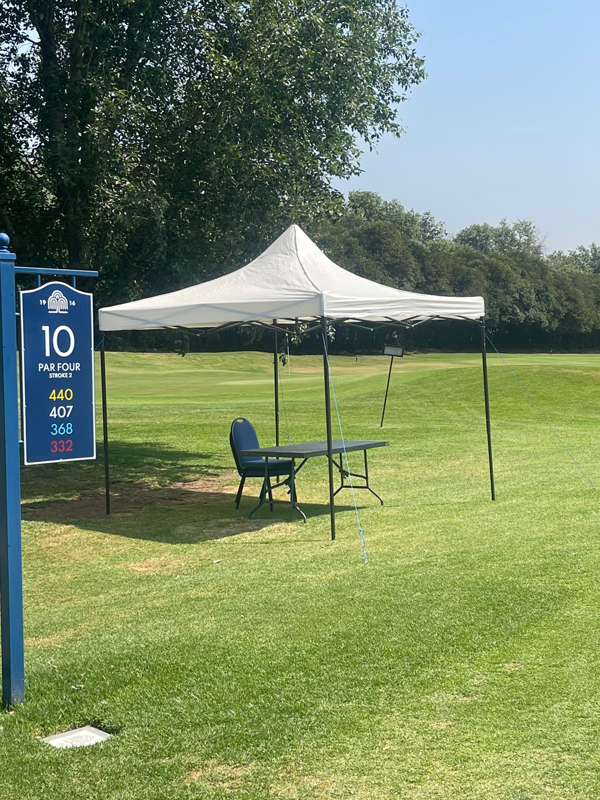 White gazebo with a table and chair on a golf course