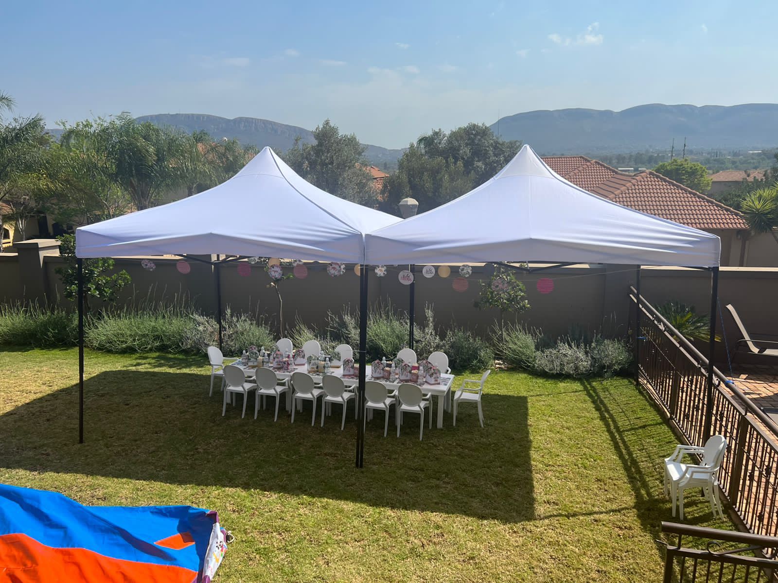 Two white gazebos set up in a garden with tables and chairs