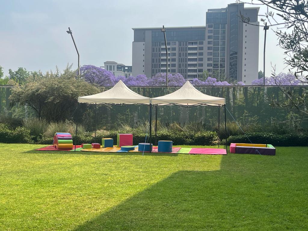 Outdoor party setup with gazebos and colorful play items on grass