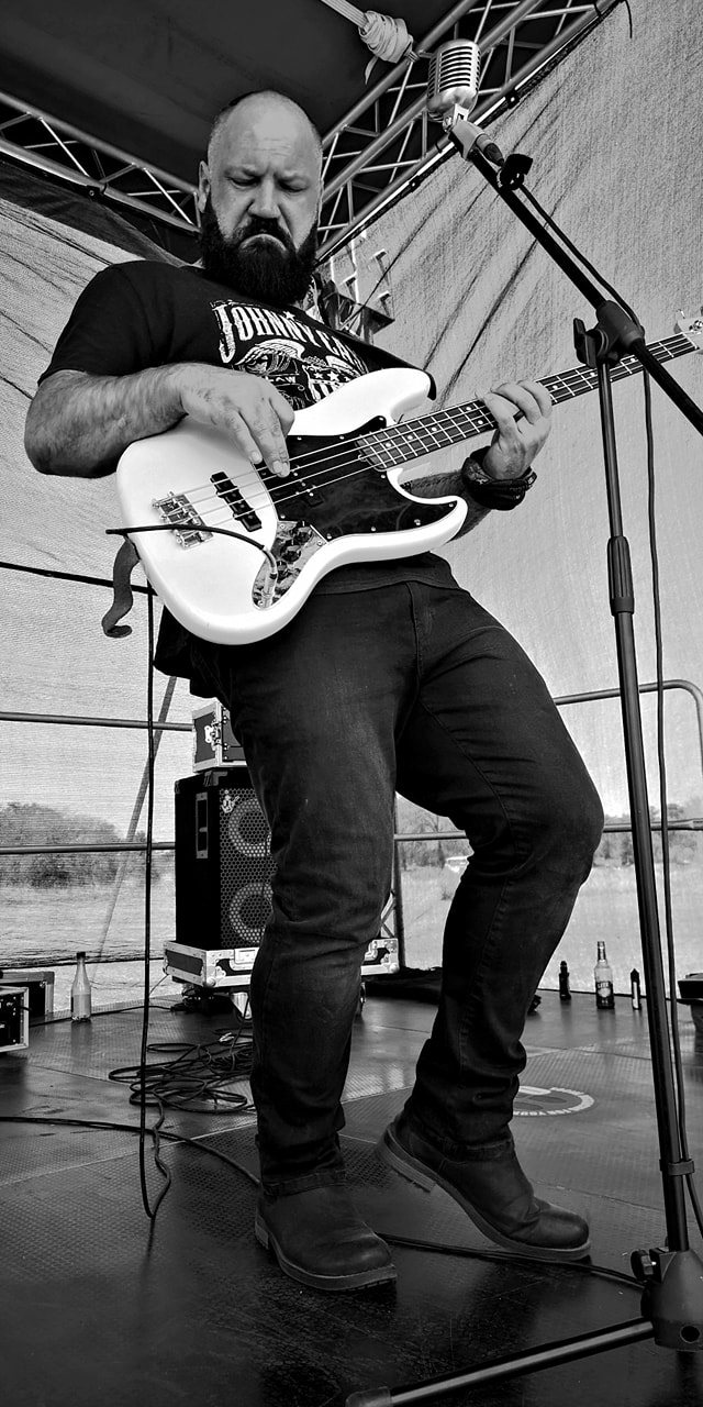 Bassist performing on stage with a white bass guitar.