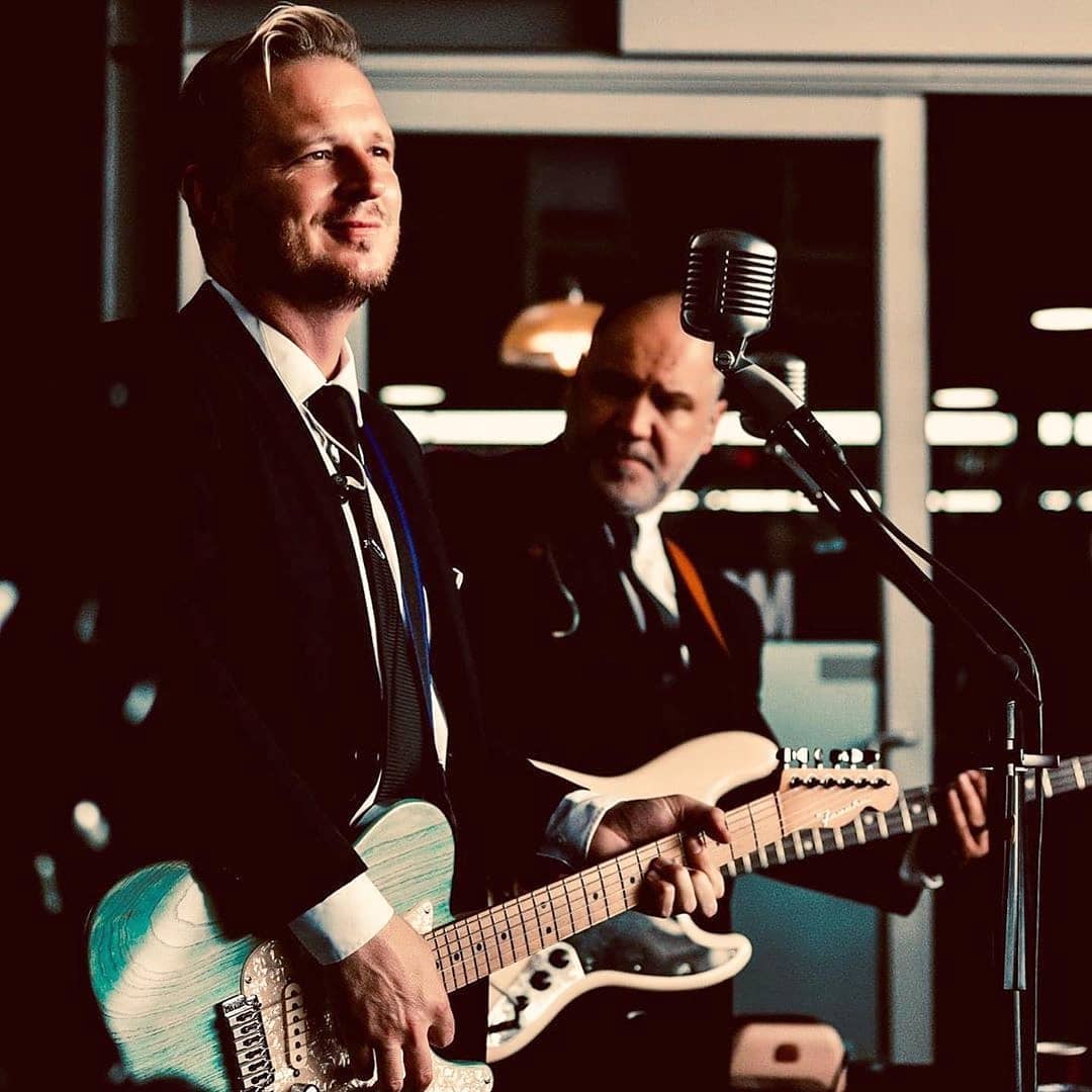 Two musicians performing on stage with guitars.