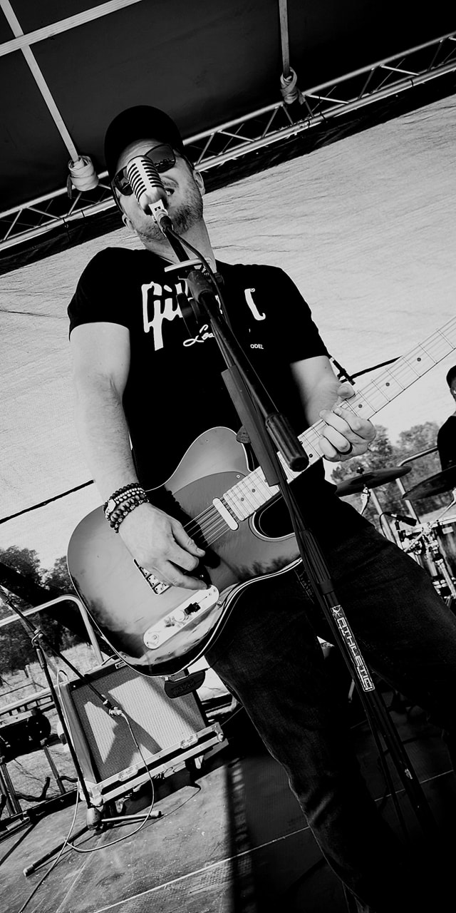 Musician performing onstage with a guitar and microphone