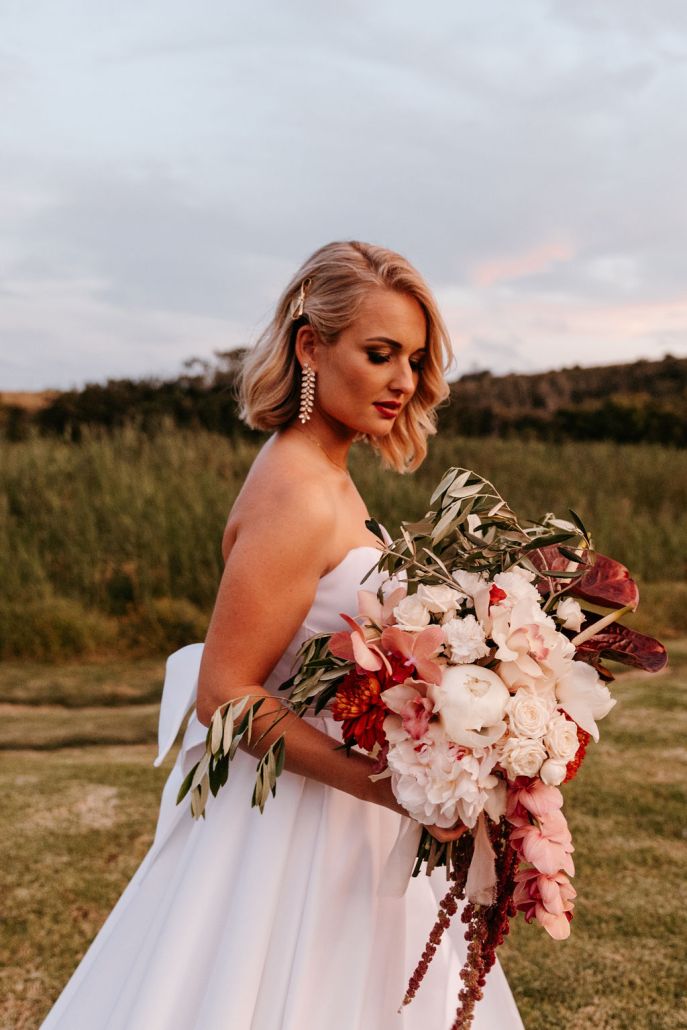 Bride in white dress holding a colorful floral bouquet
