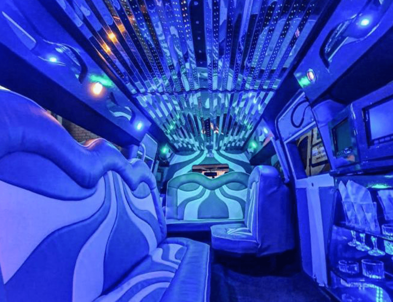 Interior of a luxurious limousine with blue lighting and comfortable seating.