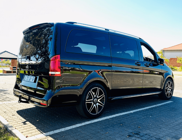 Black luxury shuttle van parked in a lot.