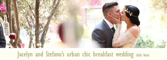 Couple kissing at an outdoor wedding with greenery