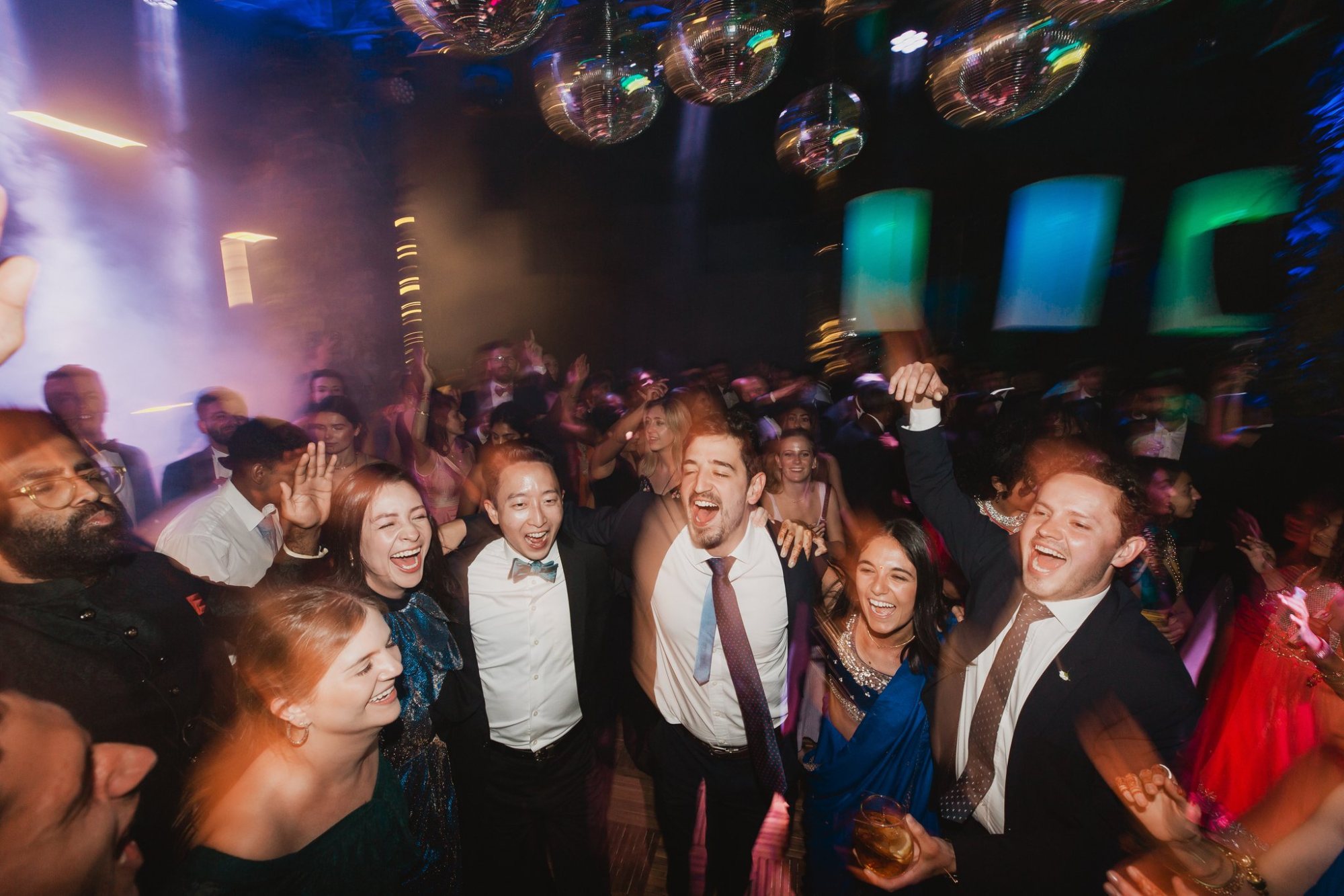 A lively dancefloor filled with guests celebrating at an event.