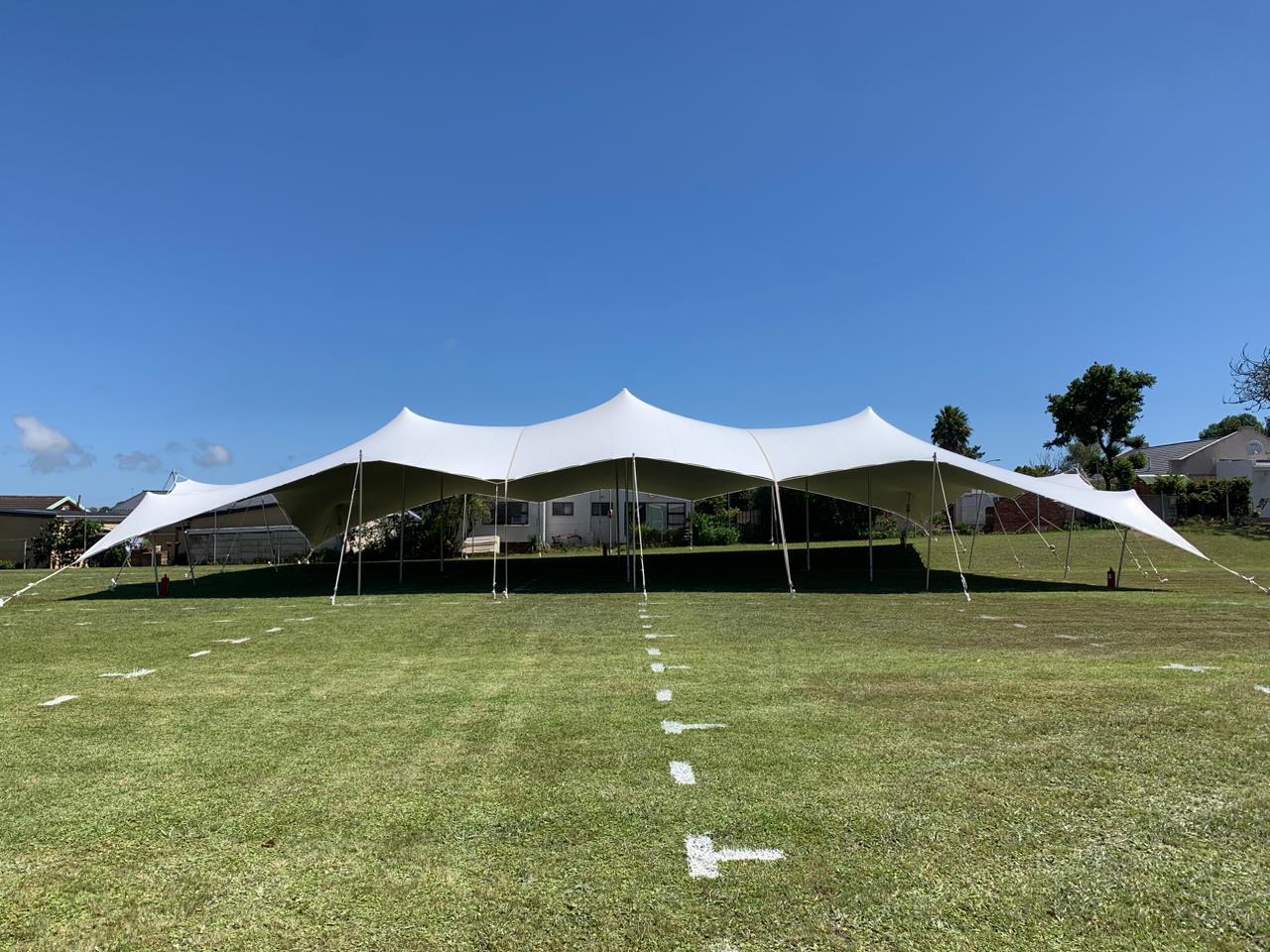 Large white marquee tent on grass under blue sky