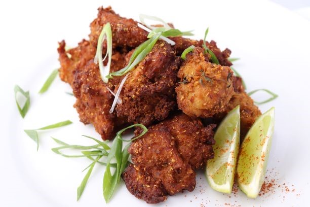Plate of Southern Fried Chickn with lime wedges and spring onions