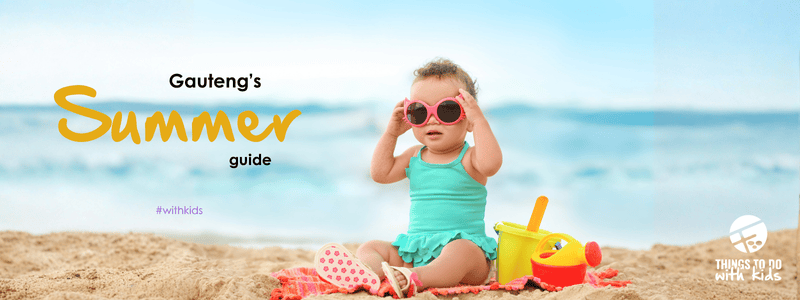 Child wearing sunglasses at the beach with summer toys.