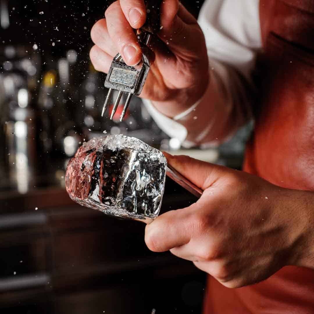 Bartender carving a block of ice for cocktails