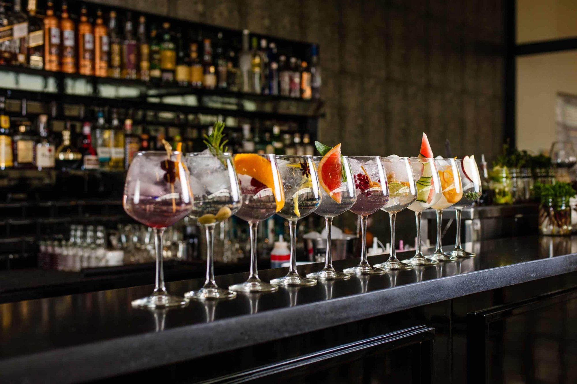 Row of cocktails with garnishes on a bar counter