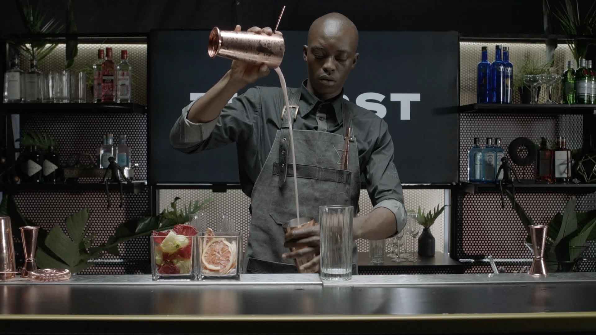 Bartender pouring a cocktail at a mobile bar setup.