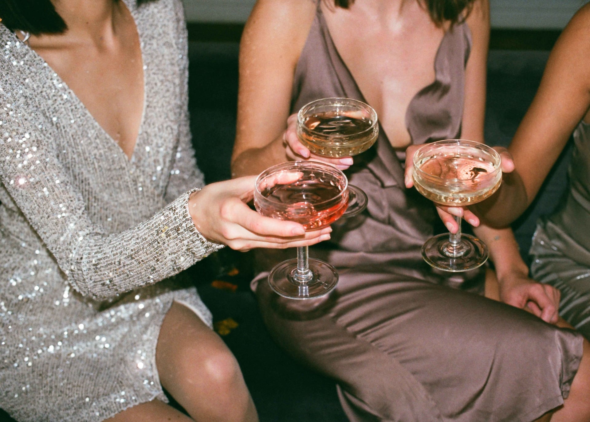 Three people holding champagne glasses with sparkling drinks