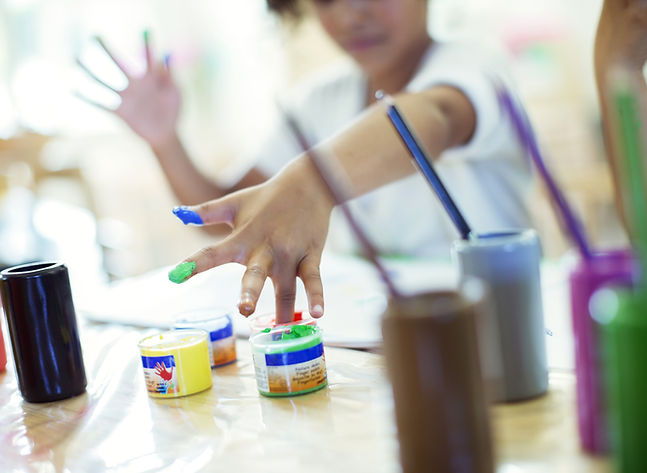 Child painting with various colors and brushes