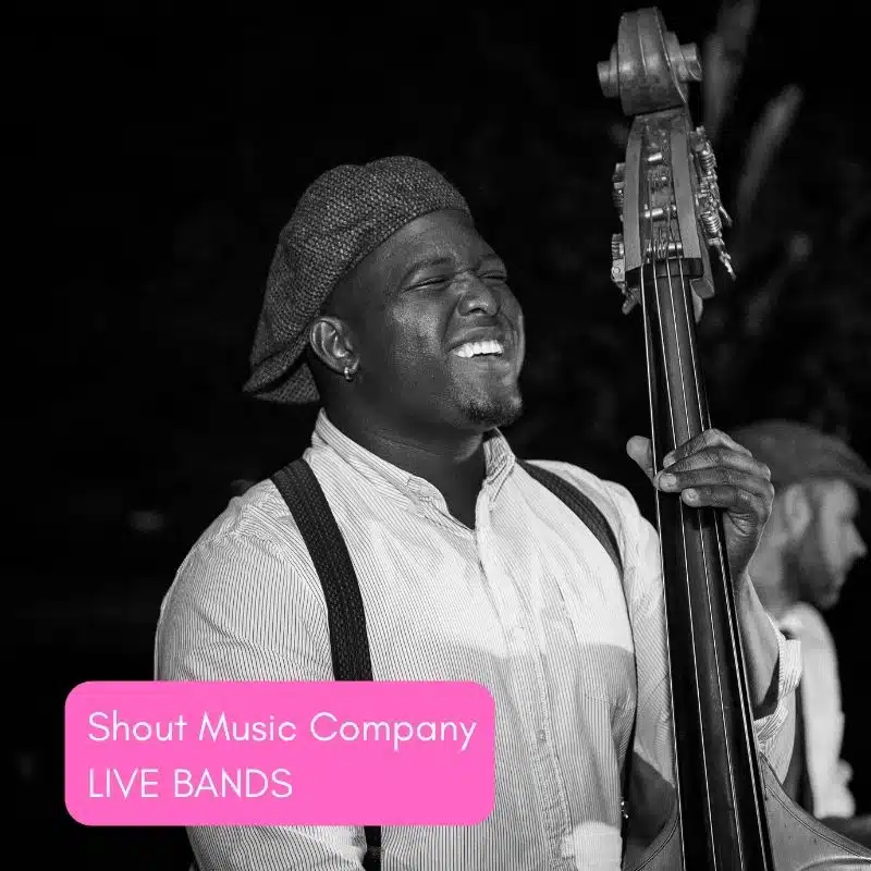 Musician playing double bass outdoors with a smile